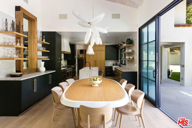 dining room featuring ceiling fan, high vaulted ceiling, and light wood-type flooring