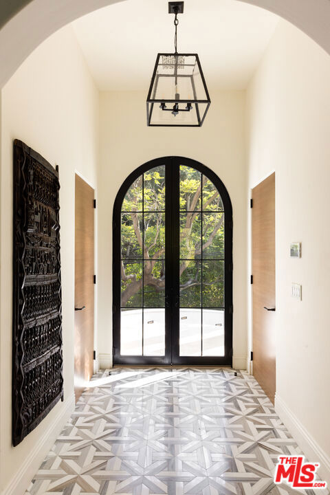 entrance foyer featuring light parquet flooring, french doors, and an inviting chandelier