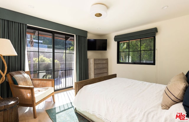 bedroom with hardwood / wood-style floors, access to outside, and multiple windows