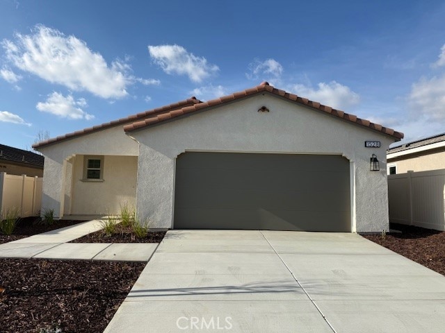 view of front of house with stucco siding, concrete driveway, a garage, and fence