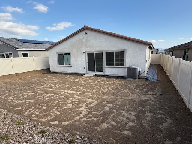 rear view of property with central air condition unit, a fenced backyard, and stucco siding