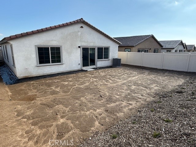 back of house with central air condition unit, stucco siding, a tiled roof, and fence