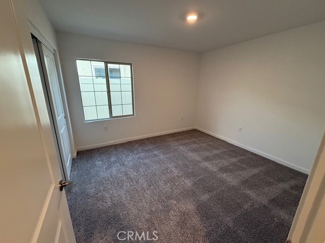 unfurnished bedroom featuring dark carpet and baseboards