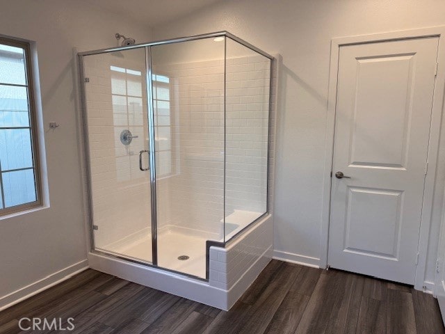 full bathroom featuring a stall shower, baseboards, and wood finished floors