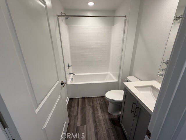 full bathroom with bathing tub / shower combination, toilet, wood finished floors, and vanity