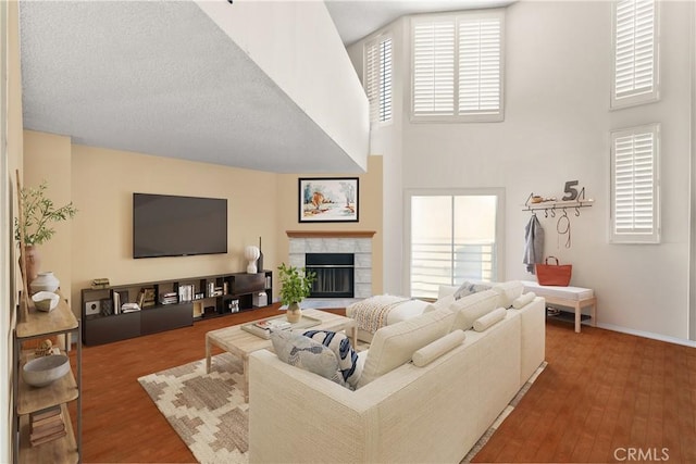 living room featuring a high ceiling, wood-type flooring, and a fireplace