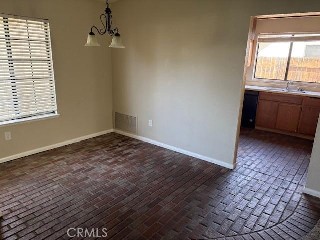 unfurnished dining area with sink and a notable chandelier