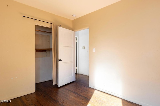 unfurnished bedroom with dark wood-type flooring and a closet