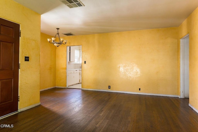 empty room featuring an inviting chandelier and dark hardwood / wood-style floors