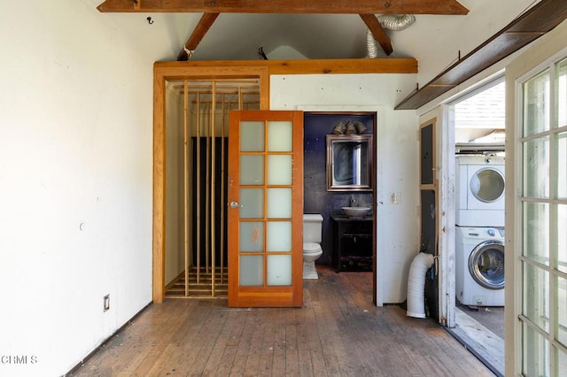 laundry area with stacked washing maching and dryer and dark wood-type flooring