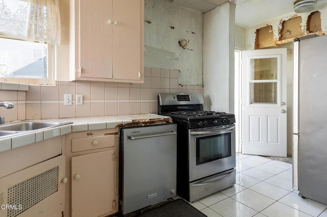 kitchen with tile countertops, decorative backsplash, sink, appliances with stainless steel finishes, and light tile patterned floors