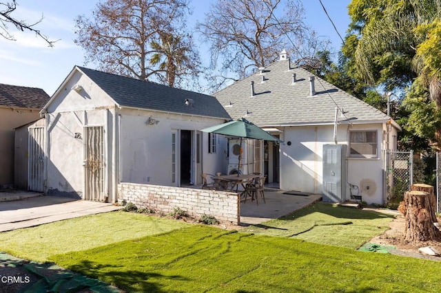 back of house with a patio area and a lawn