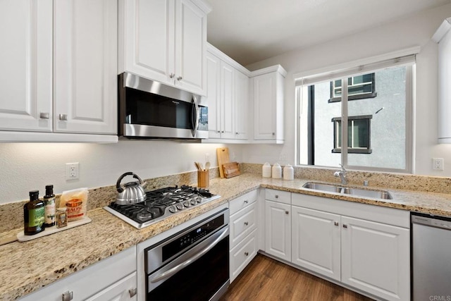 kitchen featuring dark wood-type flooring, sink, stainless steel appliances, and white cabinetry