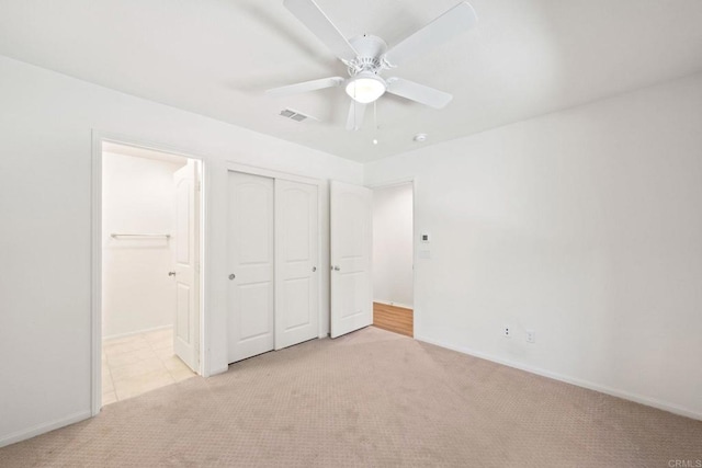 unfurnished bedroom with ceiling fan, a closet, and light carpet