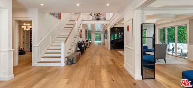 foyer entrance featuring ornamental molding, light hardwood / wood-style flooring, and a notable chandelier