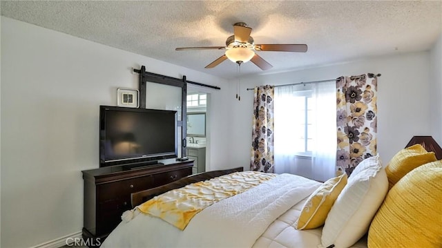 bedroom with a textured ceiling, ceiling fan, and a barn door