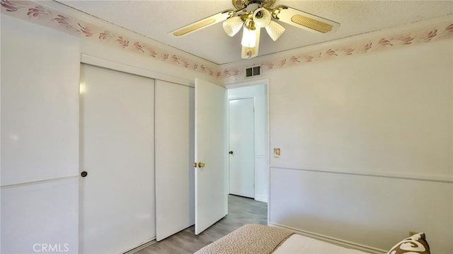 unfurnished bedroom with ceiling fan, a closet, and hardwood / wood-style floors