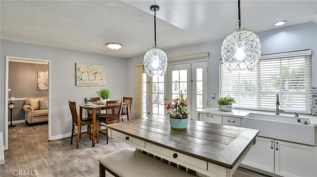 dining space with light wood-type flooring, a textured ceiling, a healthy amount of sunlight, and sink