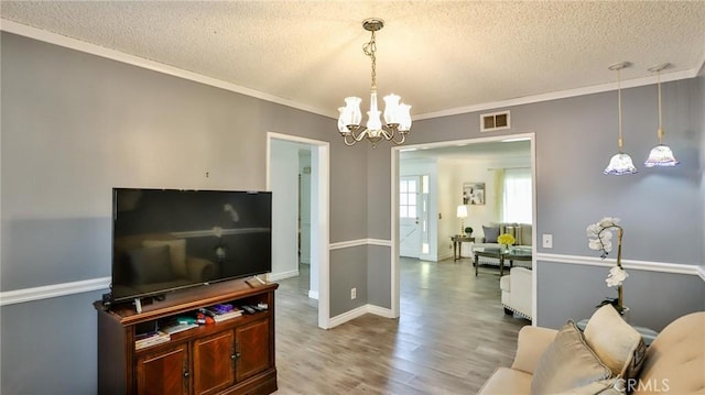 living room with wood-type flooring, crown molding, a chandelier, and a textured ceiling