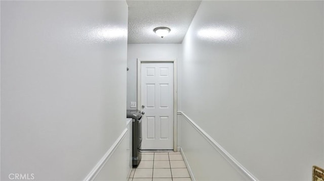 hallway with a textured ceiling and light tile patterned floors