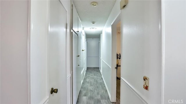 corridor featuring a textured ceiling and light wood-type flooring