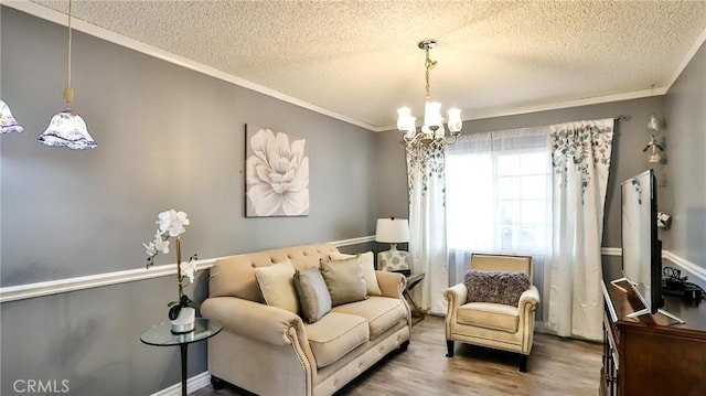 living area with wood-type flooring, crown molding, a chandelier, and a textured ceiling