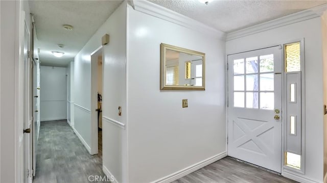 doorway with a textured ceiling, ornamental molding, and hardwood / wood-style floors