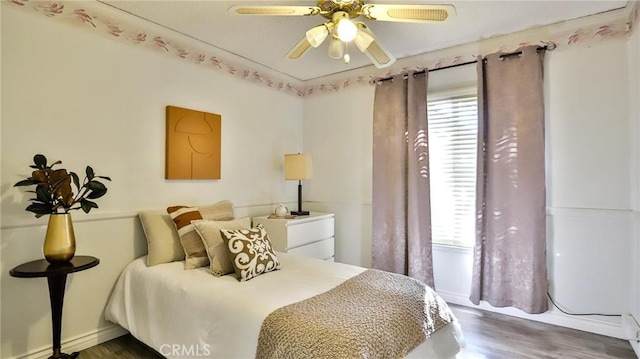 bedroom featuring ceiling fan, dark hardwood / wood-style flooring, and multiple windows