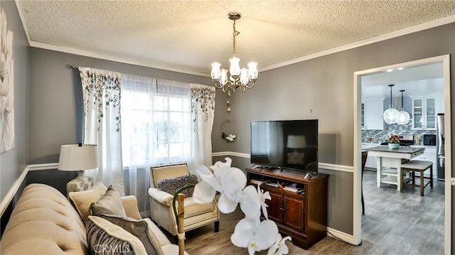 living room with hardwood / wood-style flooring, a textured ceiling, ornamental molding, and a notable chandelier