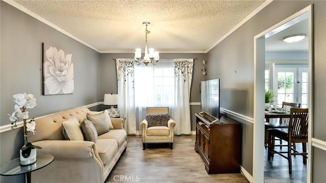 living area with a textured ceiling, an inviting chandelier, ornamental molding, and wood-type flooring