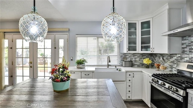 kitchen with decorative light fixtures, french doors, stainless steel range with gas cooktop, and wall chimney range hood