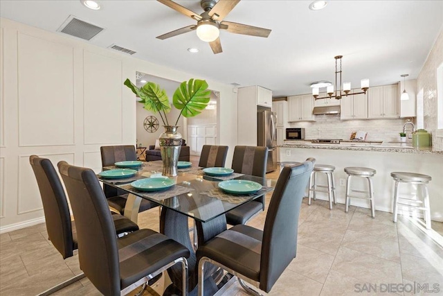 tiled dining room with ceiling fan with notable chandelier