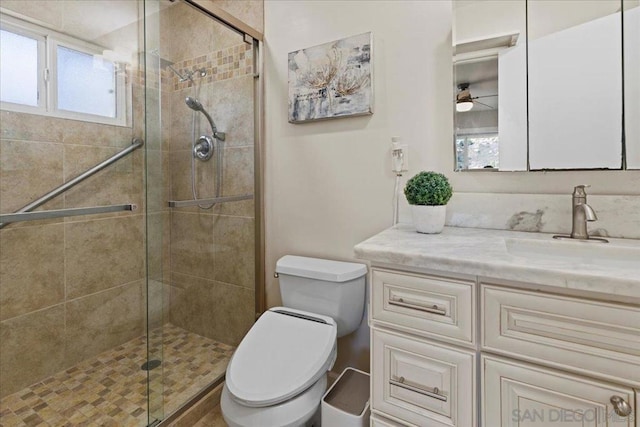 bathroom with vanity, a shower with shower door, ceiling fan, and toilet