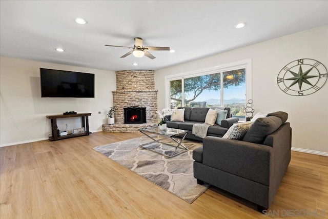 living room featuring ceiling fan, wood-type flooring, and a brick fireplace