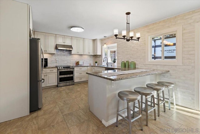 kitchen with hanging light fixtures, a kitchen breakfast bar, kitchen peninsula, an inviting chandelier, and stainless steel appliances