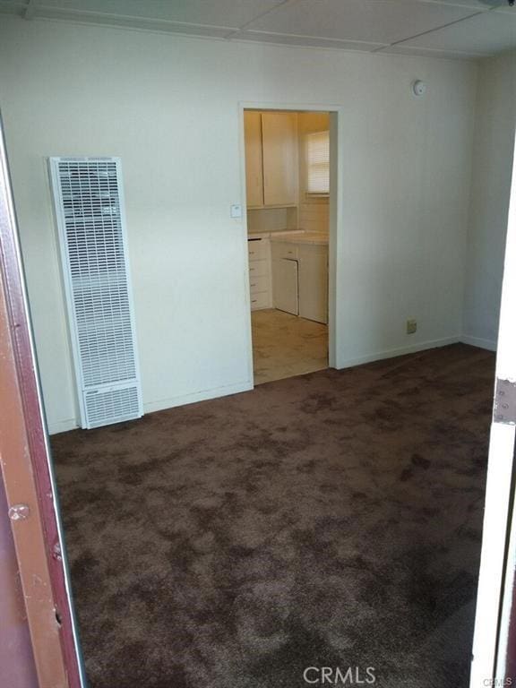 empty room featuring a heating unit and carpet flooring