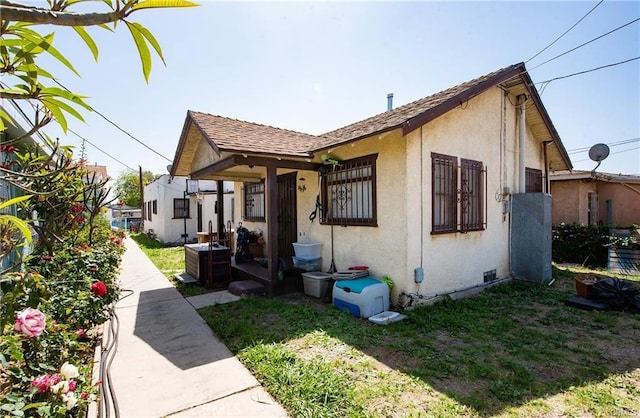 view of front of property featuring crawl space, a shingled roof, a front yard, and stucco siding