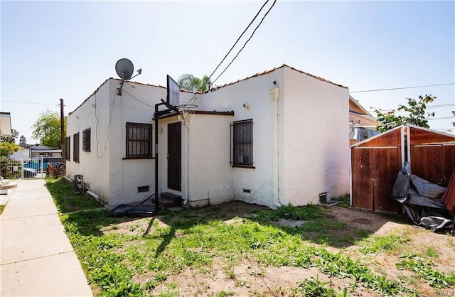 view of side of home featuring crawl space, fence, and stucco siding