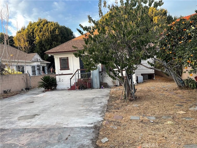 view of property hidden behind natural elements featuring fence and roof with shingles