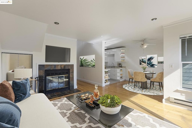 living room featuring ceiling fan, ornamental molding, a fireplace, and hardwood / wood-style flooring