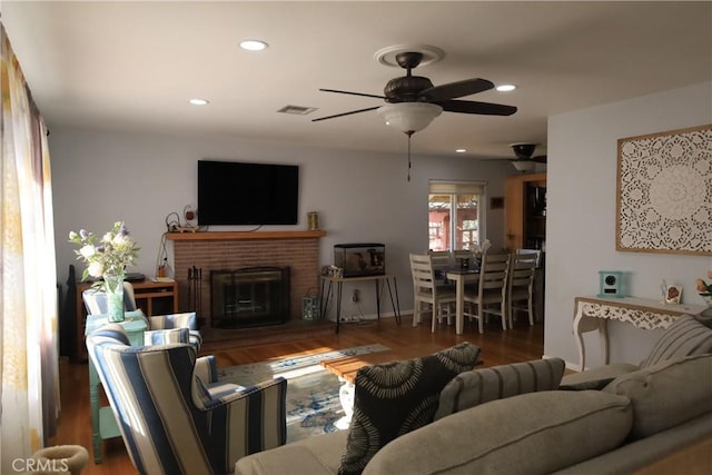 living room featuring ceiling fan, a fireplace, and wood-type flooring