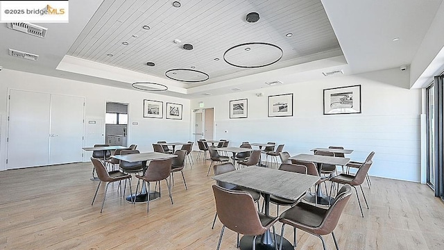 dining room with wood ceiling, light hardwood / wood-style flooring, and a tray ceiling