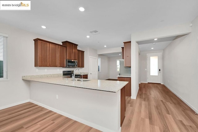 kitchen featuring light wood-type flooring, kitchen peninsula, sink, and stainless steel appliances