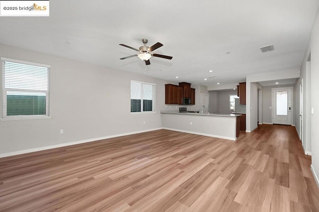 unfurnished living room featuring ceiling fan and light hardwood / wood-style flooring