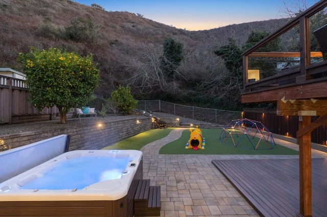 patio terrace at dusk with a hot tub and a mountain view