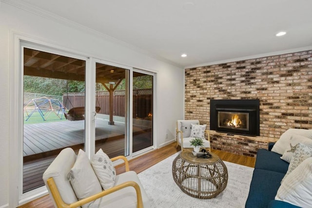 living room featuring a brick fireplace, plenty of natural light, crown molding, and hardwood / wood-style flooring