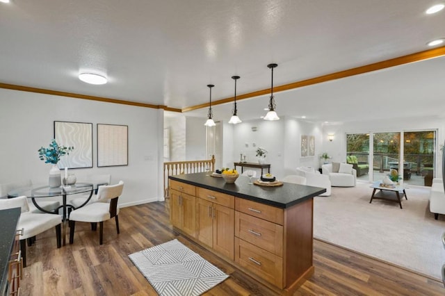 kitchen with dark wood-type flooring, hanging light fixtures, a center island, and ornamental molding