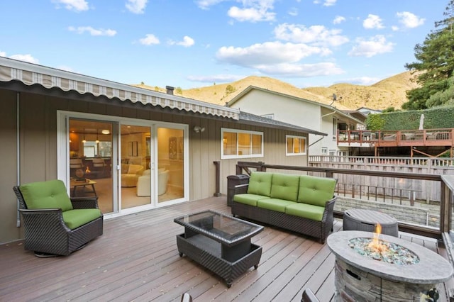 wooden deck featuring an outdoor living space with a fire pit and a mountain view