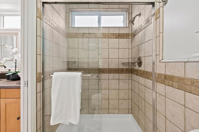 bathroom featuring a shower with door and vanity