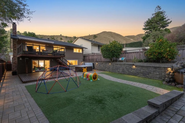 yard at dusk featuring a jacuzzi, a balcony, and a deck with mountain view